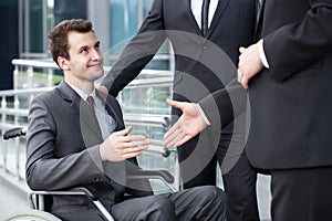 Disabled businessman shaking hand with business partners