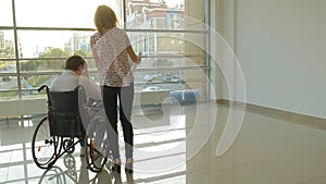 A disabled businessman on a wheelchair in a window with a drawing on a large sheet of paper, discusses work by phone