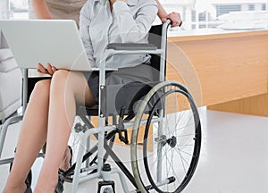 Disabled businesswoman showing laptop to colleague