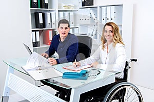 Disabled businesswoman in wheelchair and her colleague