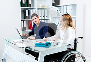 Disabled businesswoman in wheelchair and her colleague