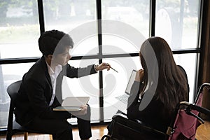 Disabled businesswoman working with her colleague in workplace.