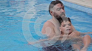 Disabled child swims, relaxes and plays with his father in a pool