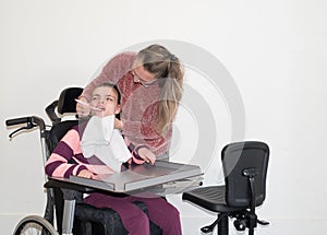 A disabled child in a wheelchair together with a voluntary care worker photo