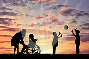 Disabled child in wheelchair crying and his mother near children play with ball