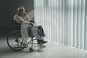Disabled elderly man looks sad near the window
