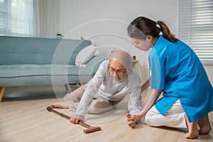 Disabled elderly old man patient with walking stick fall on floor and caring young assistant