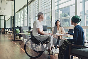 Disabled executive member in a discussion with his diverse and multi racial business team photo