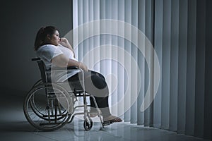 Disabled fat woman looks pensive near the window