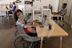 Disabled female executive using laptop at desk