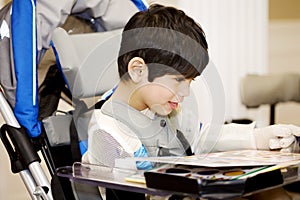Disabled four year old boy studying in wheelchair