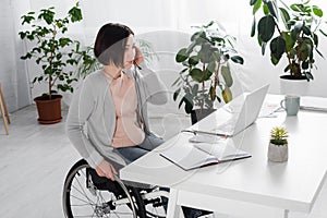 Disabled freelancer using headset near laptop