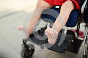 Disabled girl sitting in wheelchair. Close up photo of her legs spasticity muscles . Child cerebral palsy. Disability. Inclusion