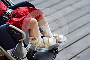 Disabled girl sitting in wheelchair. On her legs orthosis. Child cerebral palsy. Inclusion photo