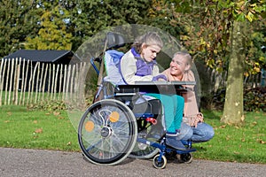 A disabled girl in a wheelchair outside with a care assistant