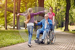 Disabled grandfather in wheelchair welcoming his granddaughter photo