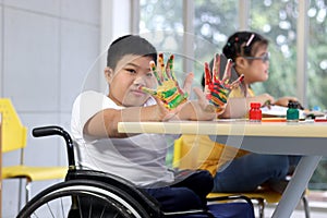 Disabled kids classroom, children having fun during study at school, kids learning together, schoolboy on wheelchair showing his
