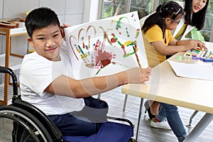 Disabled kids classroom, children having fun during study at school, kids learning together, schoolboy on wheelchair showing his
