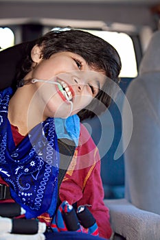 Disabled little boy sitting in carseat inside vehicle