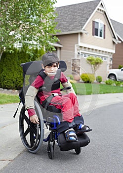 Disabled little boy in wheelchair outdoors