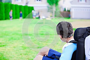 Disabled little boy in wheelchair watching children play on play