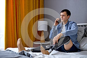 disabled male with artificial leg talking on phone at home. adult guy with prostheses