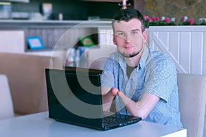 Disabled man with amputated two stump hands in cafe with laptop looks at camera.