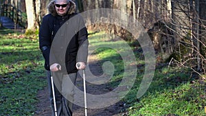 Disabled man on crutches at outdoor near benches in park