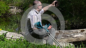 Disabled man with crutches using tablet PC near river