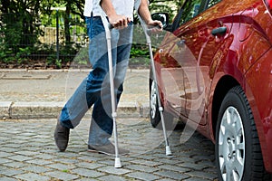 Disabled man with crutches walking near care