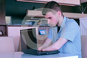 Disabled man freelancer with amputated two stump hands in cafe works on laptop.