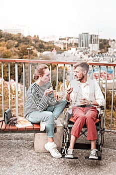 Disabled man frowning and eating fruit with his friend