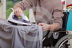 Disabled man ironing shirt