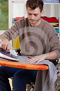 Disabled man ironing shirts at home