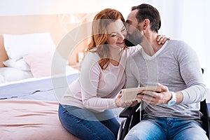 Disabled man kissing a pretty happy woman