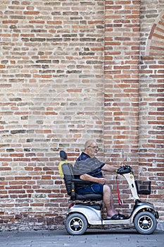 Disabled man on a mini car in front of a brick wall