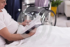 Disabled man reading in bed.