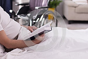 Disabled man reading in bed.