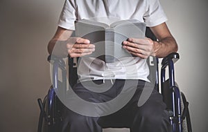 Disabled man reading Bible in home. Religion