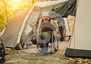 Disabled man resting in a campsite with friends. Wheelchair in the forest