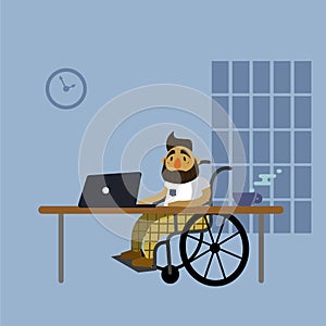 A disabled man sitting in a wheelchair at the desk with laptop