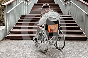 Disabled man sitting in wheelchair in front of the stairs