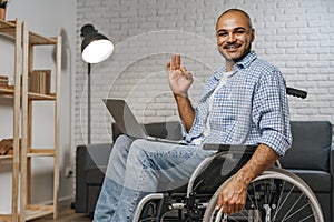 Disabled man sitting in a wheelchair and using laptop