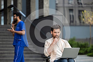 Disabled man sitting in a wheelchair and working on laptop