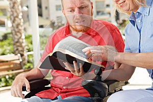 Disabled man studying Holy Bible.