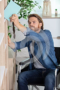 disabled man taking book from shelf