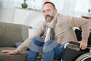 disabled man tries to sit on sofa