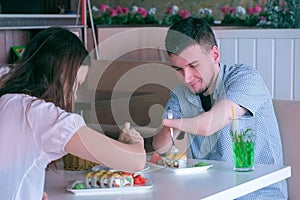 Disabled man of two amputated stump hands on date with woman in cafe eats rolls.