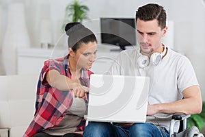 Disabled man using laptop sitting next to girlfriend