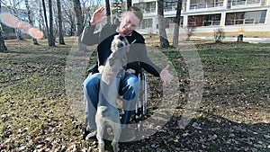 A disabled man on a walk plays with a dog